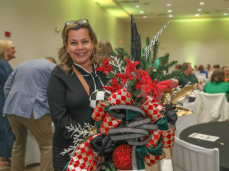 Smiling woman holds large bouquet of red flowers.