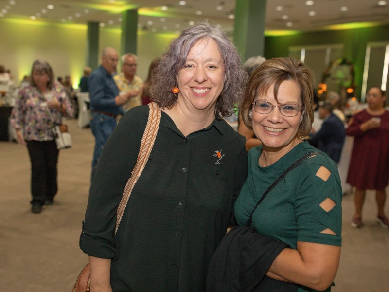 Two women standing close and smiling.