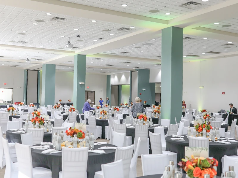 Elegant event space decorated with white linens and bright floral arrangements.